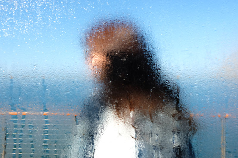 Человек сфотографирован через окно с каплями воды