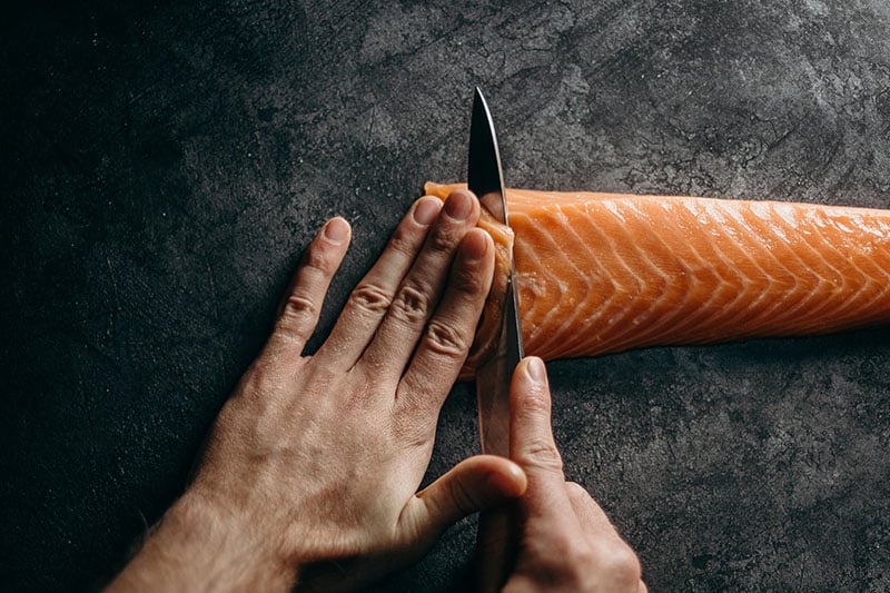 Руки с ножом для резки лосося