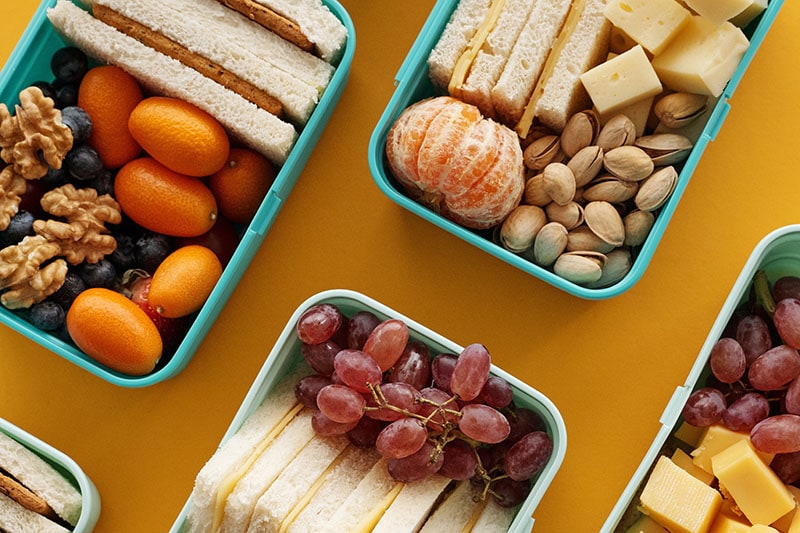 Плоская фото еда в синих контейнерах и желтом фоне