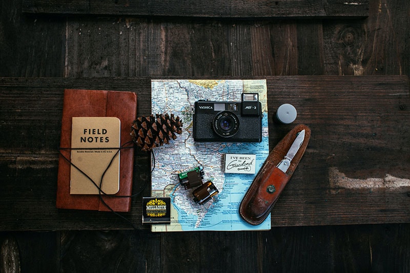 Плоское фото с камерой и картой на деревянном столе